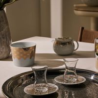 طقم تمرة بالتعاون مع رزان العزوني سترايبس المؤلف من فنجانين عربيين للشاي مع صحنيهما باللون الذهبي صلصال طقم تمرة بالتعاون مع رزان العزوني سترايبس المؤلف من فنجانين عربيين للشاي مع صحنيهما باللون الذهبي